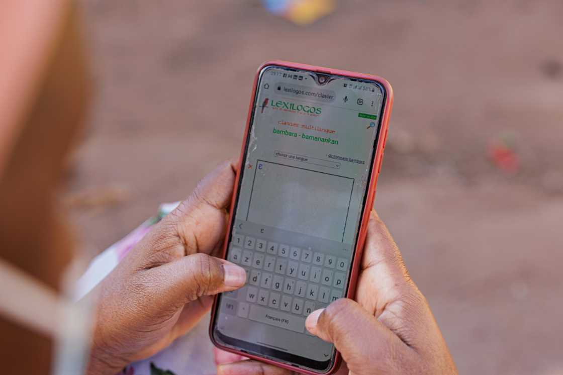 Tech support: A woman uses a dictionary app to help her type a message in Bambara on her smartphone Tech support: A woman uses a dictionary app to help her type a message in Bambara on her smartphone