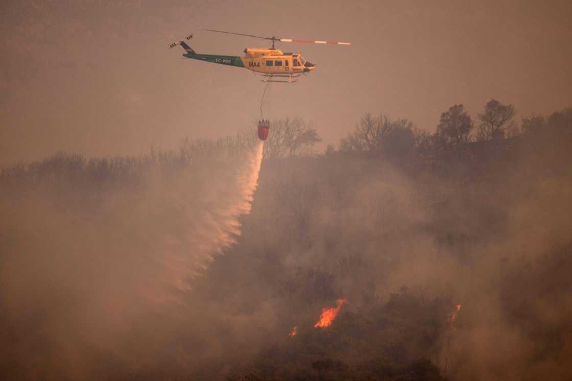 A helicopter douses a wildfire in Spain's Malaga province on July 15 A helicopter douses a wildfire in Spain's Malaga province on July 15