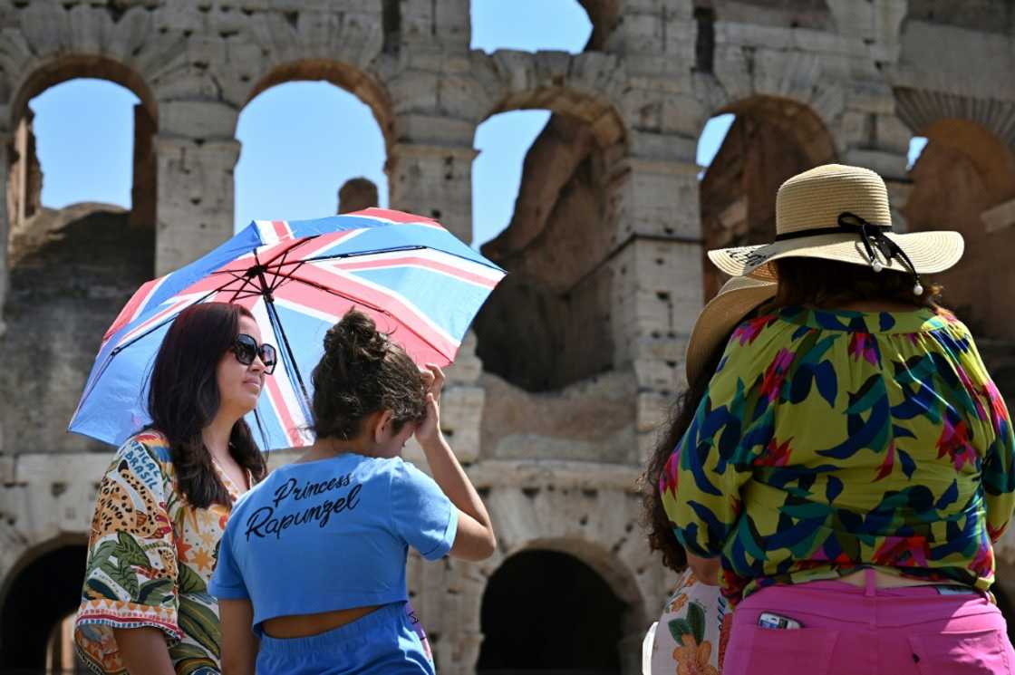 Tourists sheltered from the sun with umbrellas at the Colosseum in Rome Tourists sheltered from the sun with umbrellas at the Colosseum in Rome