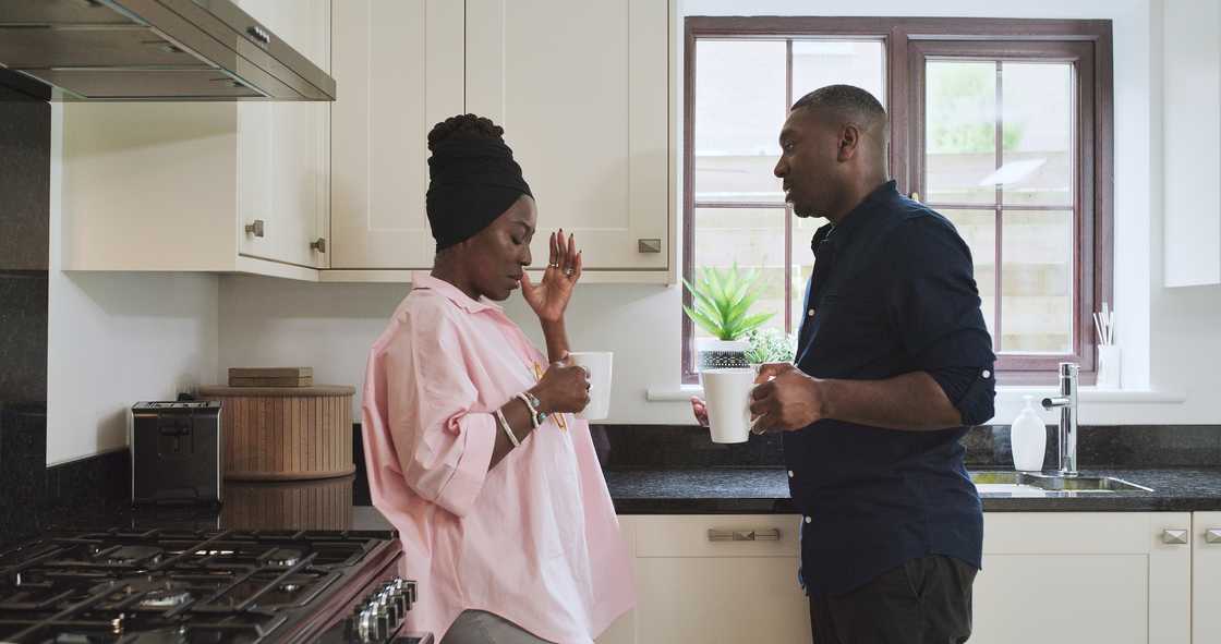 A black couple argue in a kitchen. A black couple argue in a kitchen.