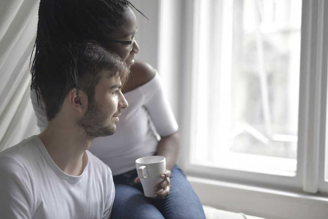 A couple sits by a window, quietly looking outside while sharing a calm moment. A couple sits by a window, quietly looking outside while sharing a calm moment.