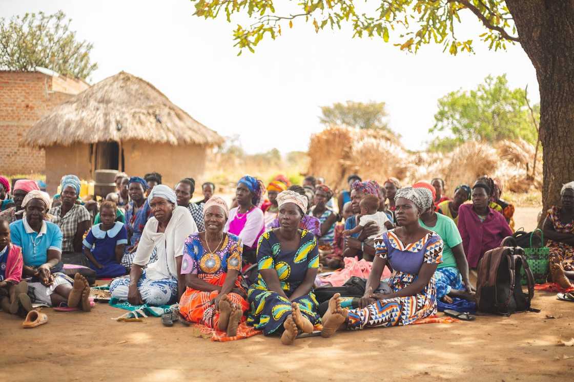 Rural women seated outdoors during a community gathering. Rural women seated outdoors during a community gathering.