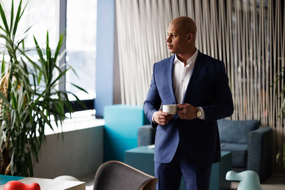Elegant African businessman holding a cup of coffee. Elegant African businessman holding a cup of coffee.