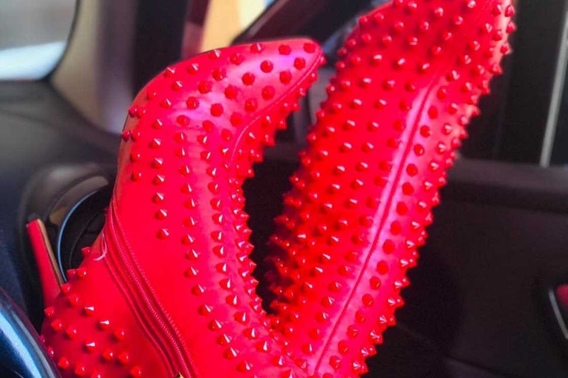 A person is wearing a pair of red Christian Louboutin boots