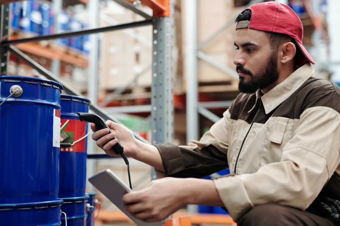 A man using a scanner wearing a snapback cap backwards