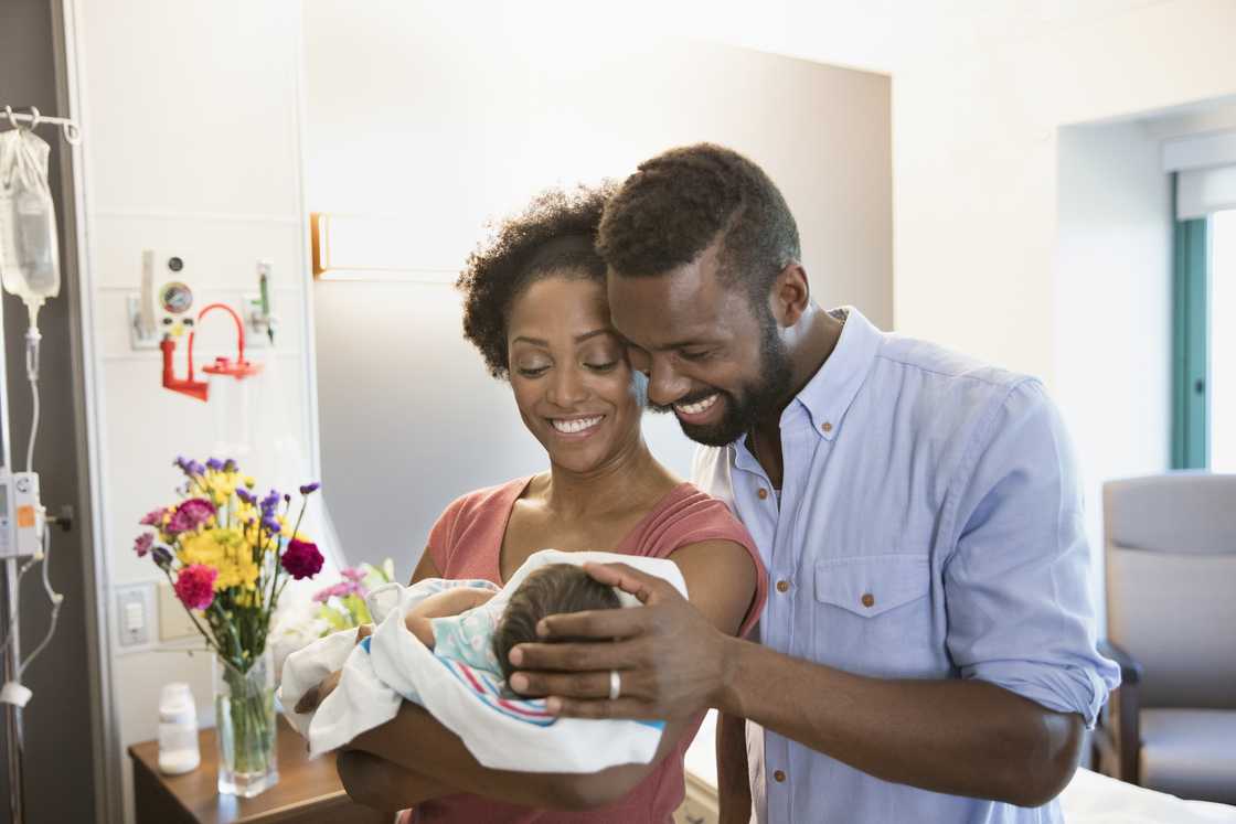 A couple holds their baby in their arms. A couple holds their baby in their arms.