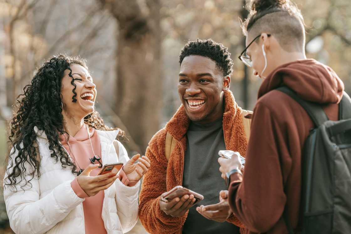 Diverse friends with smartphones in the park