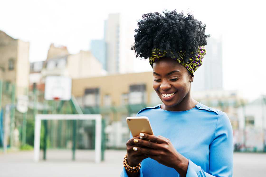 A smiling woman is using her smartphone.