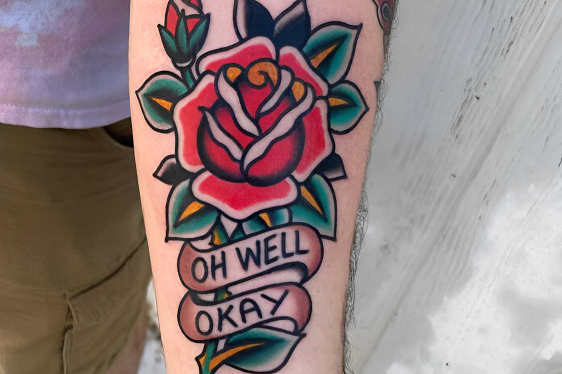 Forearm traditional rose tattoo with some writings