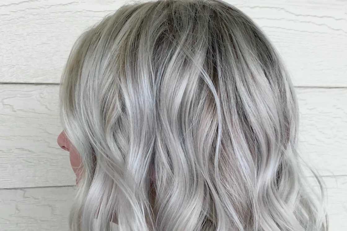 A lady is rocking a mid-length wavy layered grey lob A lady is rocking a mid-length wavy layered grey lob