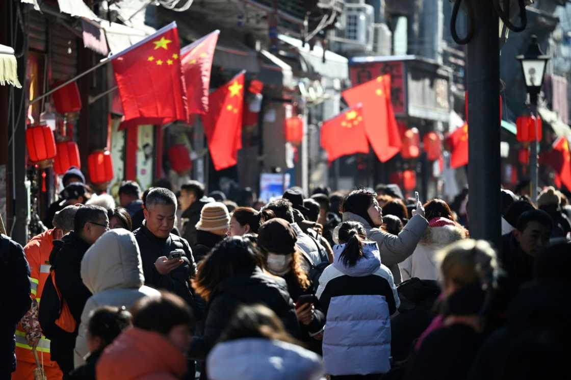 People walk below Chinese flags in an alley near a popular shopping street during the Lunar New Year holiday in Beijing People walk below Chinese flags in an alley near a popular shopping street during the Lunar New Year holiday in Beijing