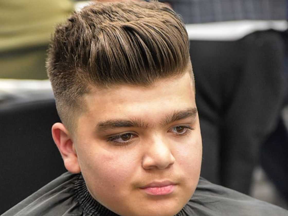 A teenage is at the barbershop recieving a classic quiff cut A teenage is at the barbershop recieving a classic quiff cut