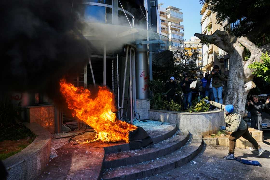 A protester throws a brick at a bank after setting fire to tyres during a demonstration in Beirut A protester throws a brick at a bank after setting fire to tyres during a demonstration in Beirut
