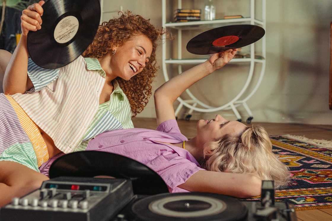 Two young women lying on the floor while holding vinyl records