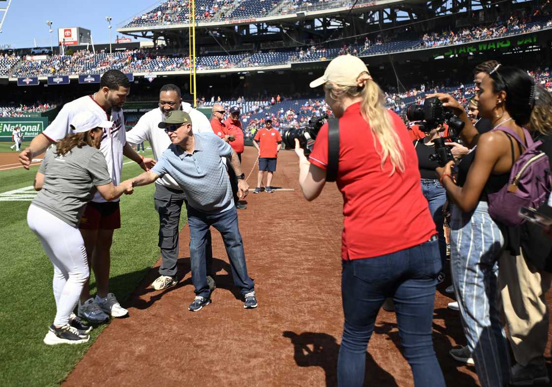 Caleb Williams poses for a photo as his mother, Dayna Price, left, shakes hands with Nationals owner Mark Lerner, with his father, Carl Williams, standing behind Lerner.