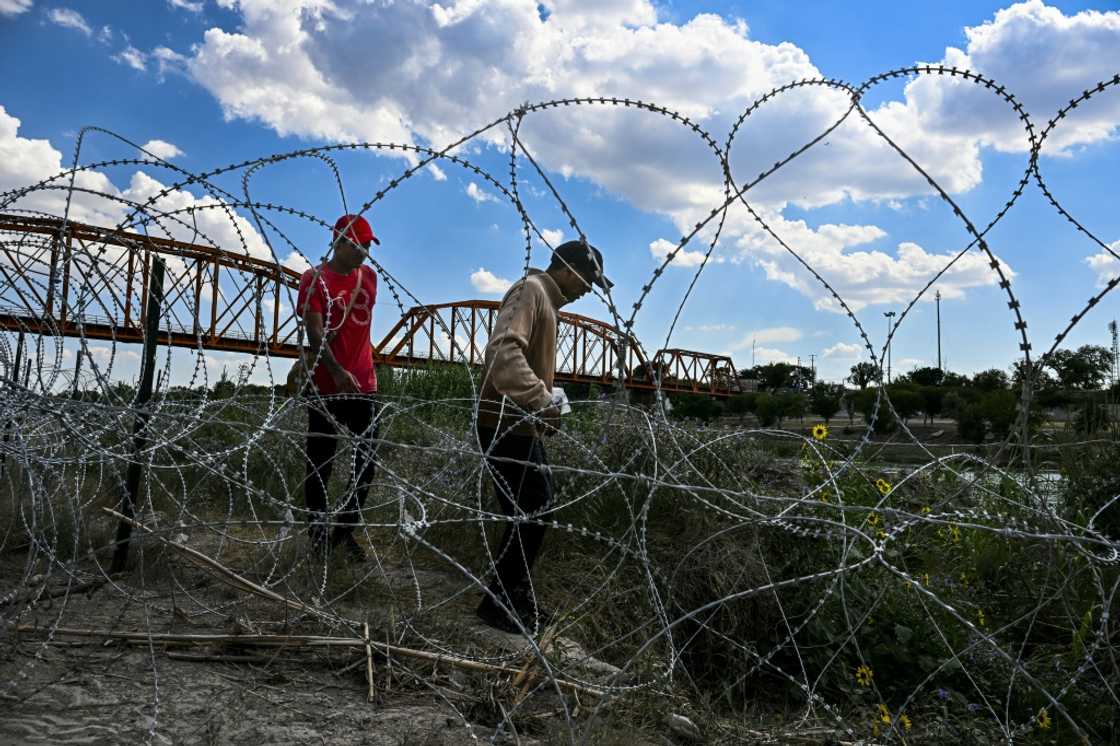 Migrants walk past concertina wire after successfully crossing into Texas Migrants walk past concertina wire after successfully crossing into Texas