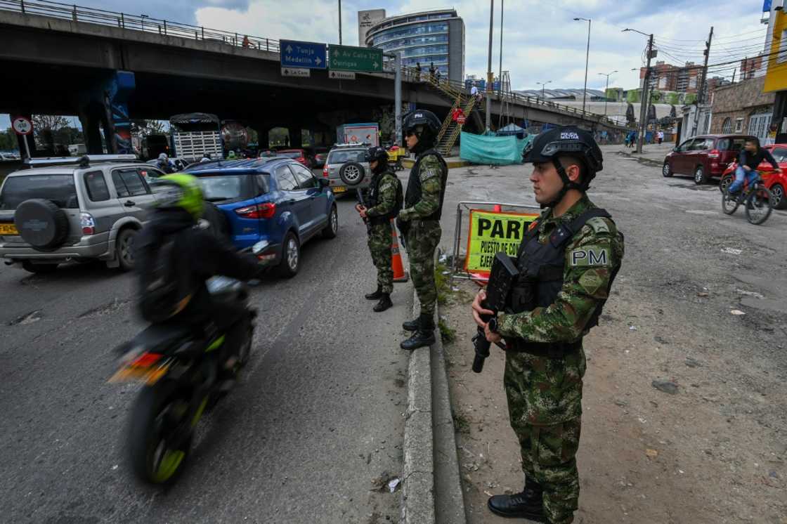 Soldiers stand guard at a checkpoint on a road entering Bogota, on June 18, 2022, a day before the presidential runoff election