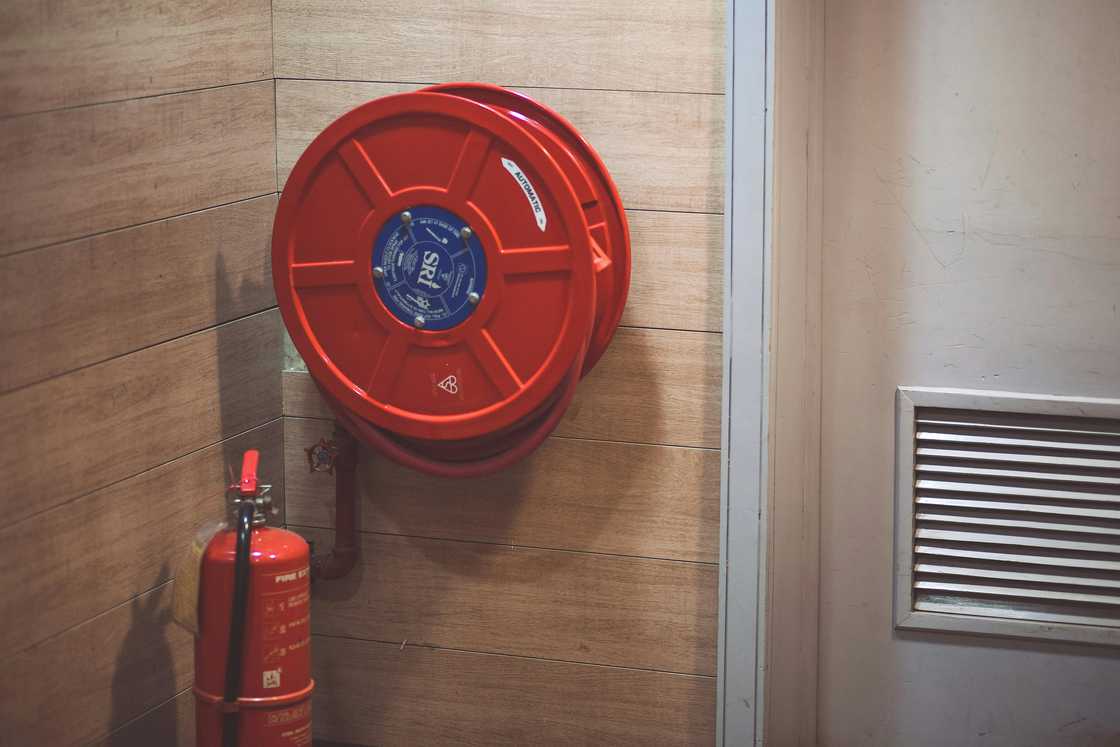 A red fire extinguisher below a hose reel A red fire extinguisher below a hose reel