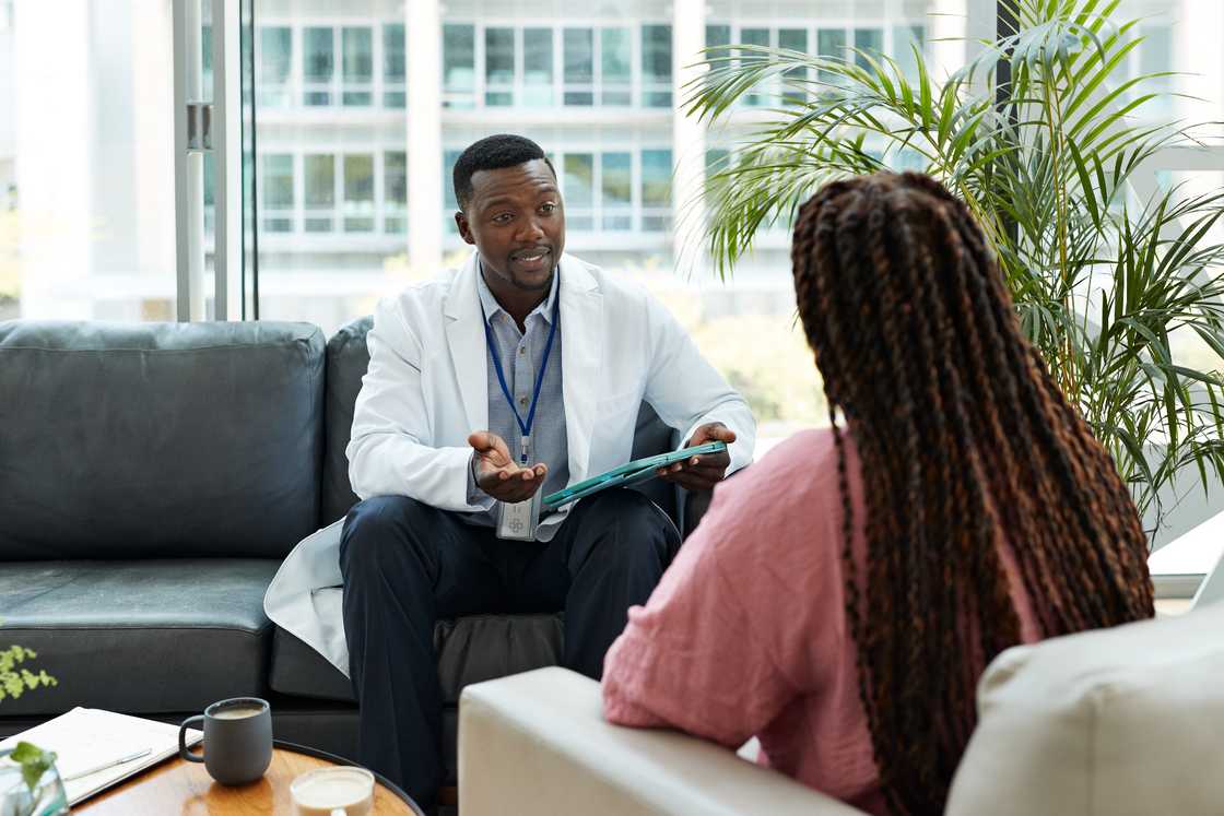 A healthcare professional holding a tablet PC and advising a patient