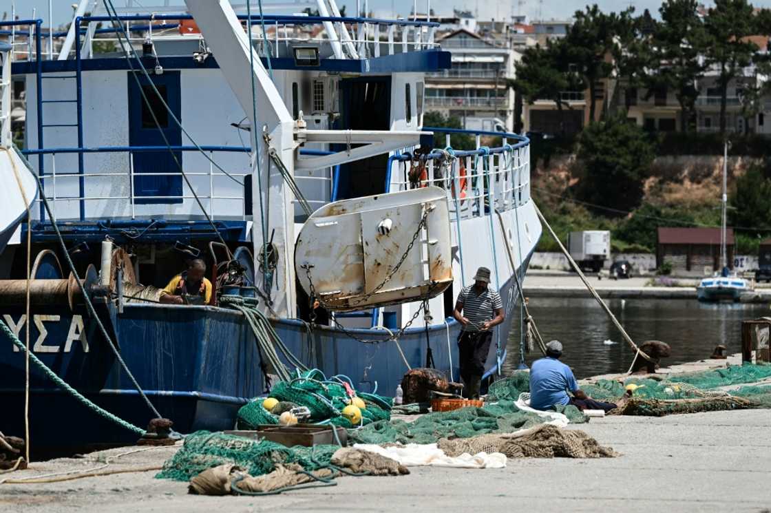 Workers handle a fishing net near a trawler docked at the port of Nea Michaniona, in northern Greece Workers handle a fishing net near a trawler docked at the port of Nea Michaniona, in northern Greece