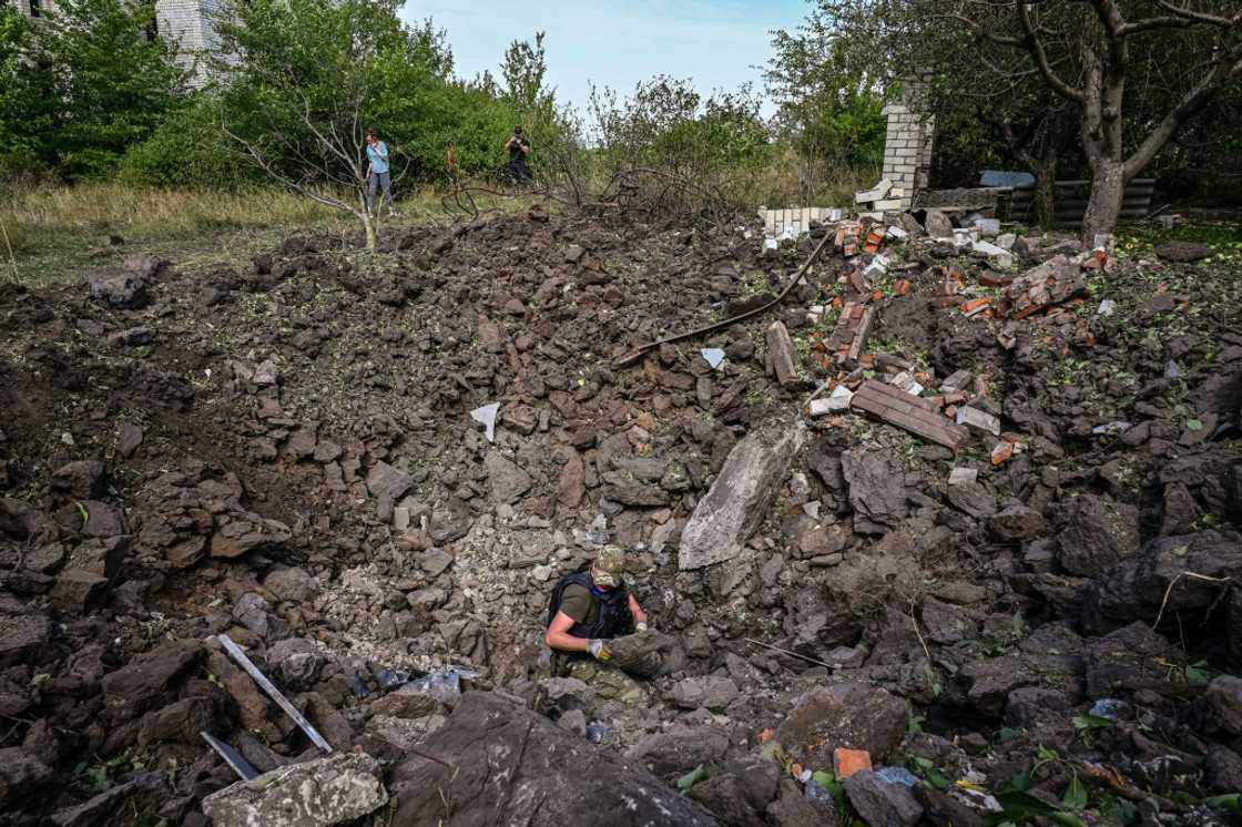 A Ukrainian deminer examines a crater following a missile strike in Rohan village near the city of Kharkiv on August 24, 2022, three days before Ukraine marks its anniversary of independence