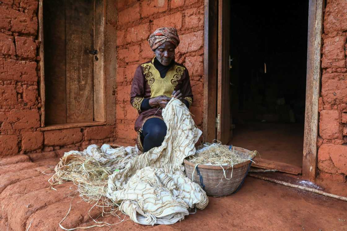 Hard work: Solange Yougo embroiders an as yet undyed piece of ndop cloth at her home in Baham Hard work: Solange Yougo embroiders an as yet undyed piece of ndop cloth at her home in Baham