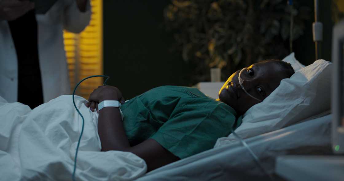 A mother in bed looks towards an empty baby cot.