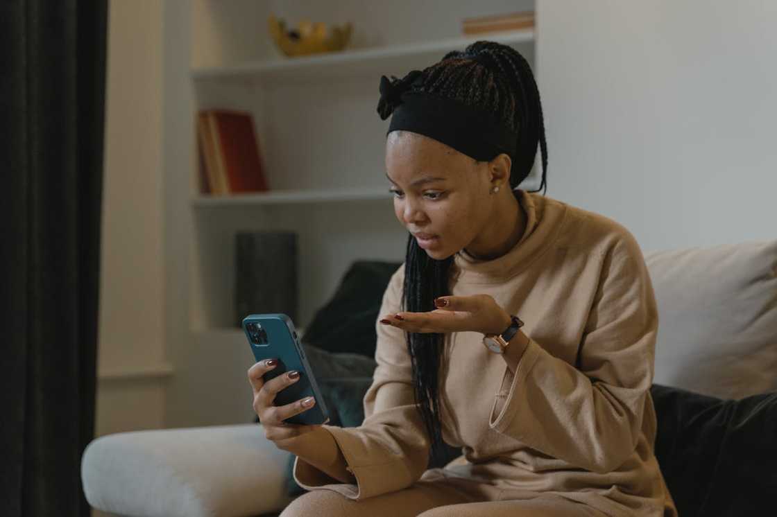 A young woman scrolls through social media alone in her flat. A young woman scrolls through social media alone in her flat.