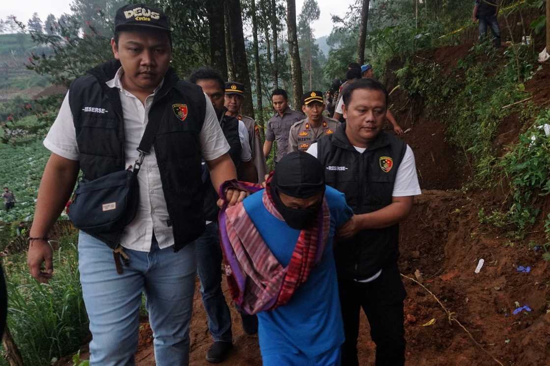 Police escorting accused serial killer shaman Slamet Tohari (C) at Balun village in Banjarnegara