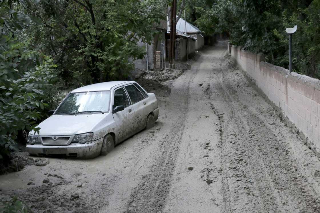 A car partially buried in mud on a road in the Firouzkouh area A car partially buried in mud on a road in the Firouzkouh area