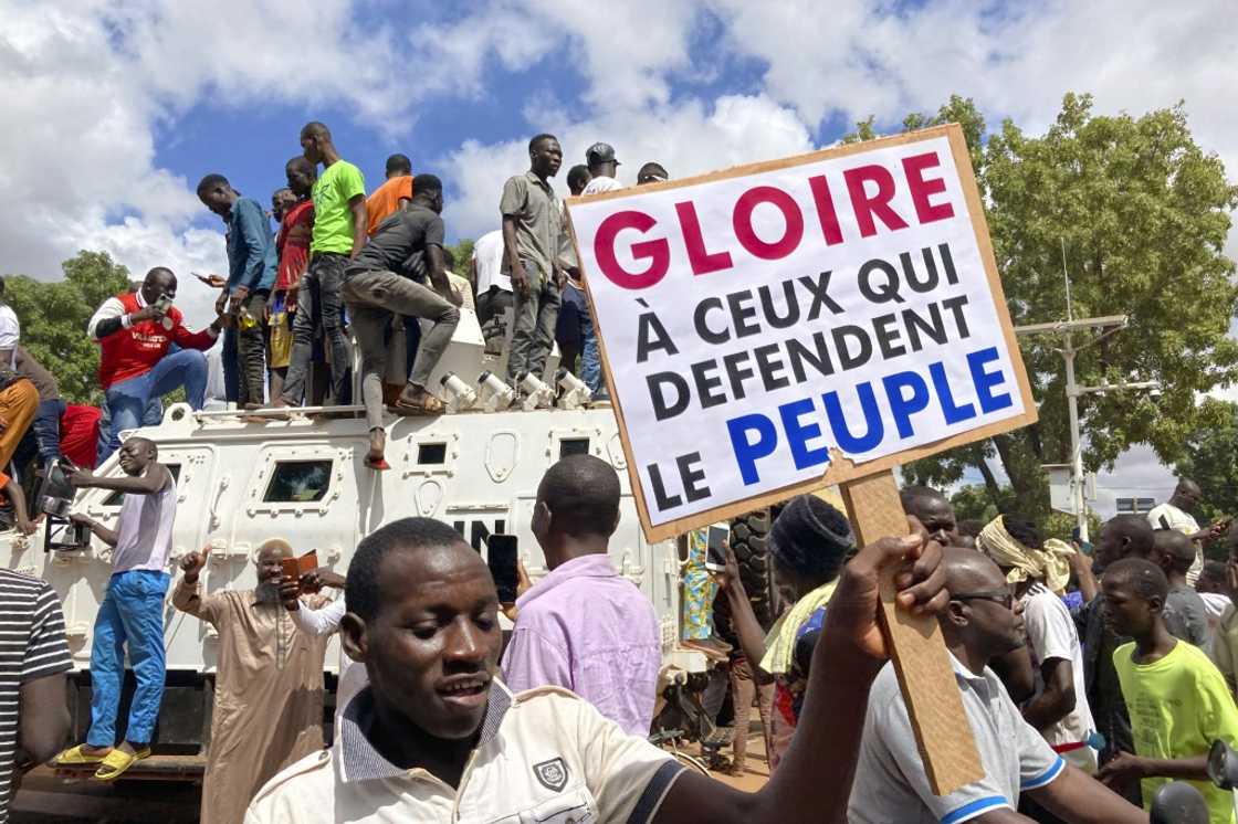 Protestors in the Burkina Faso Ouagadougou stand atop a UN armoured vehicle last weekend in support of the latest coup. The sign reads 'Glory to those who defend the people' Protestors in the Burkina Faso Ouagadougou stand atop a UN armoured vehicle last weekend in support of the latest coup. The sign reads 'Glory to those who defend the people'