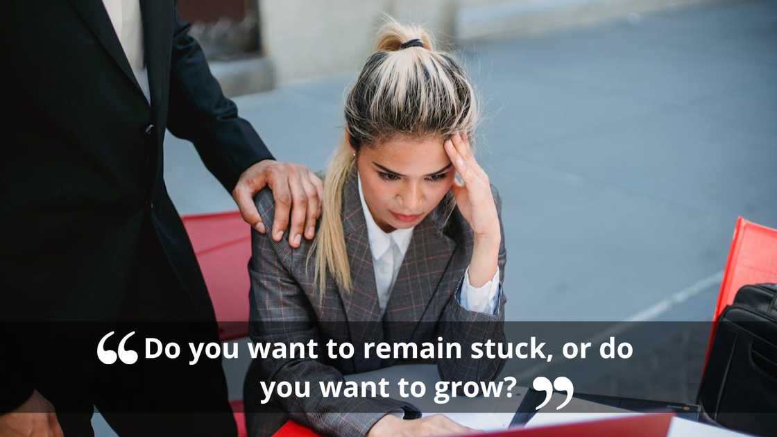 An anxious woman holding her head while a suited colleague rests a reassuring hand on her shoulder. An anxious woman holding her head while a suited colleague rests a reassuring hand on her shoulder.