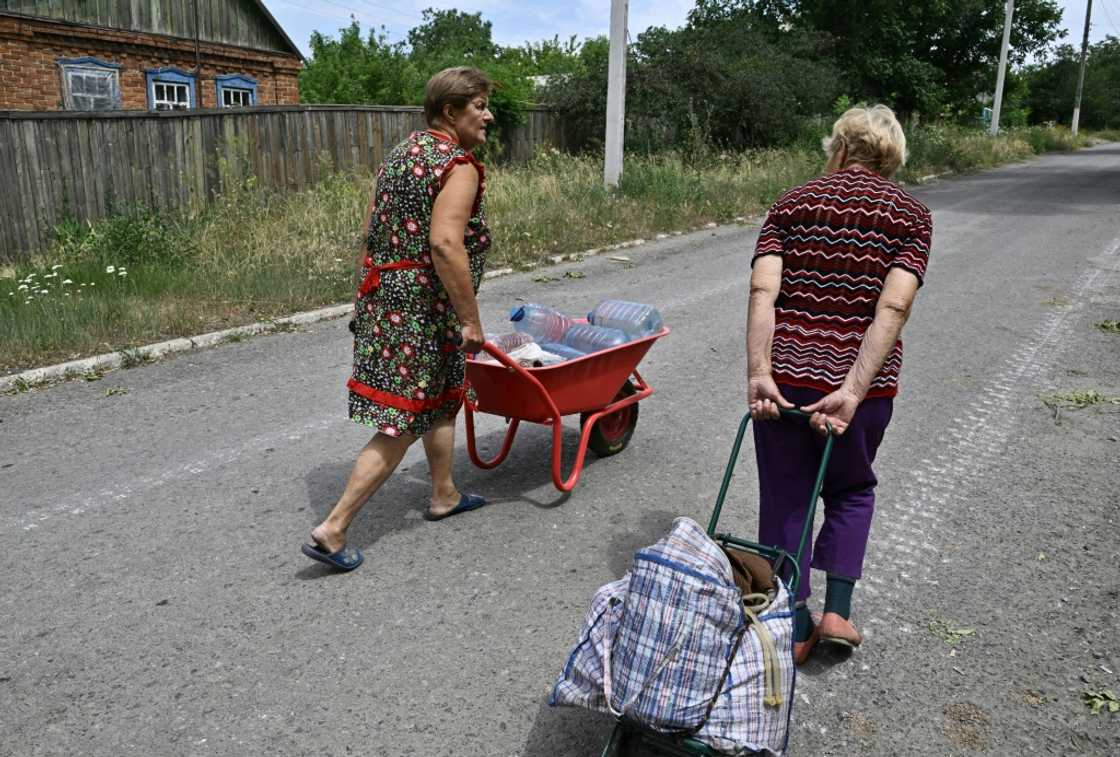Women transport water bottles in a wheelbarrow and trolley Women transport water bottles in a wheelbarrow and trolley
