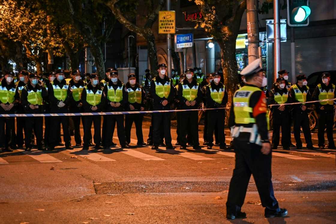 Police officers block Wulumuqi street, named for Urumqi in Mandarin, in Shanghai, where protests have taken place against China's zero-Covid policy