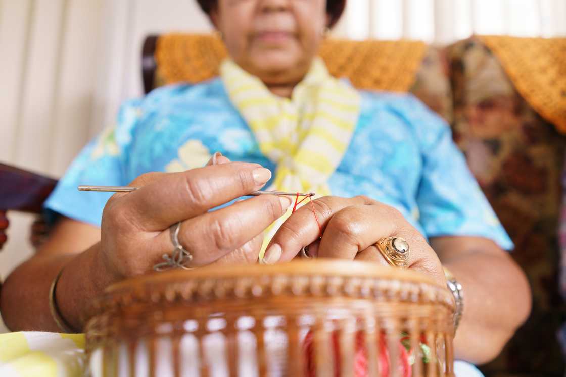 An elderly woman knitting in a cozy living room. An elderly woman knitting in a cozy living room.