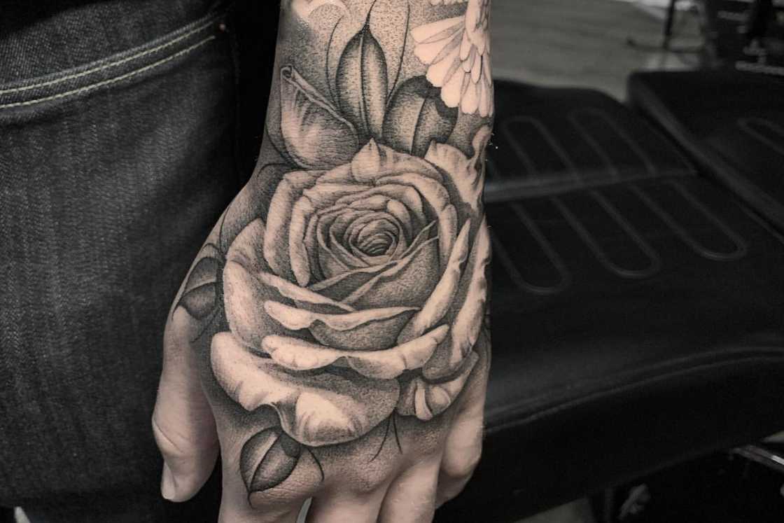 A large black and gray rose hand tattoo A large black and gray rose hand tattoo