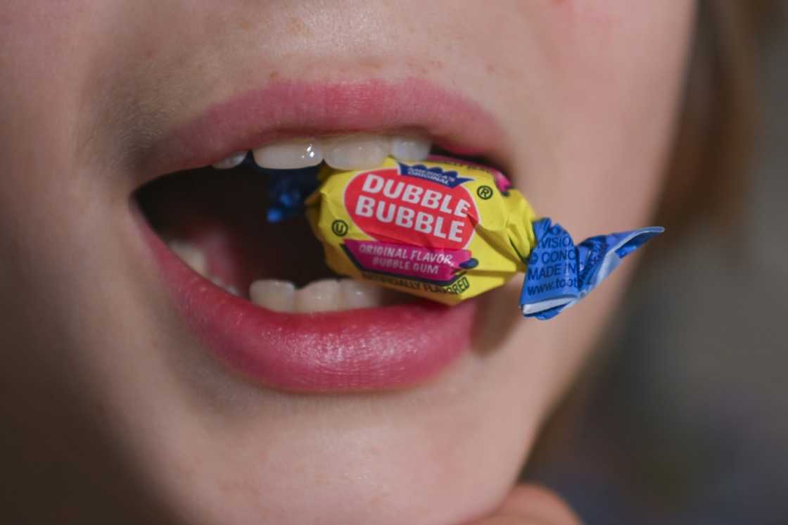 A boy holds a wrapped Dubble Bubble Bubble Gum candy in his mouth, a product that uses Red Dye No 3, in this illustration photograph on December 27, 2024