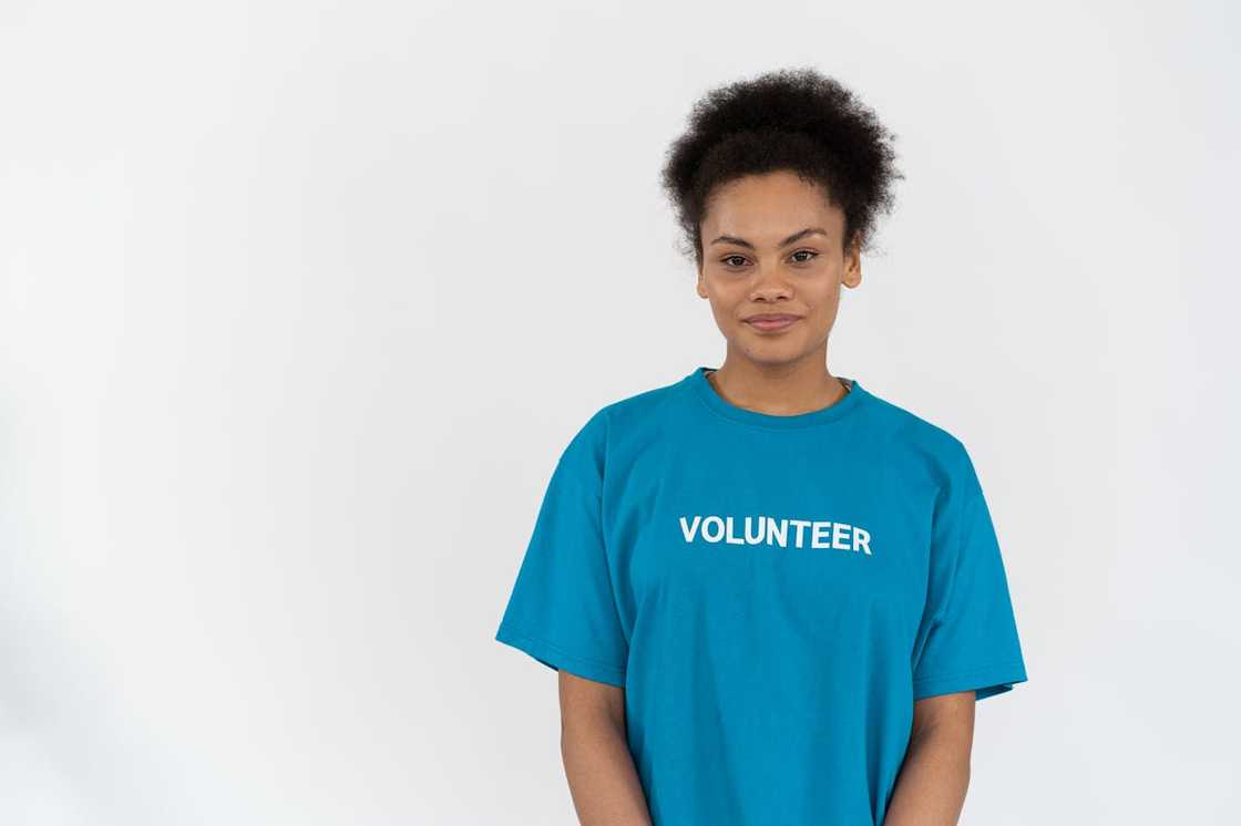 A woman wearing a volunteer shirt stands against a plain background. A woman wearing a volunteer shirt stands against a plain background.