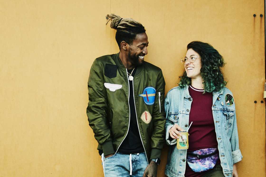 Portrait of smiling friends standing in front of yellow wall