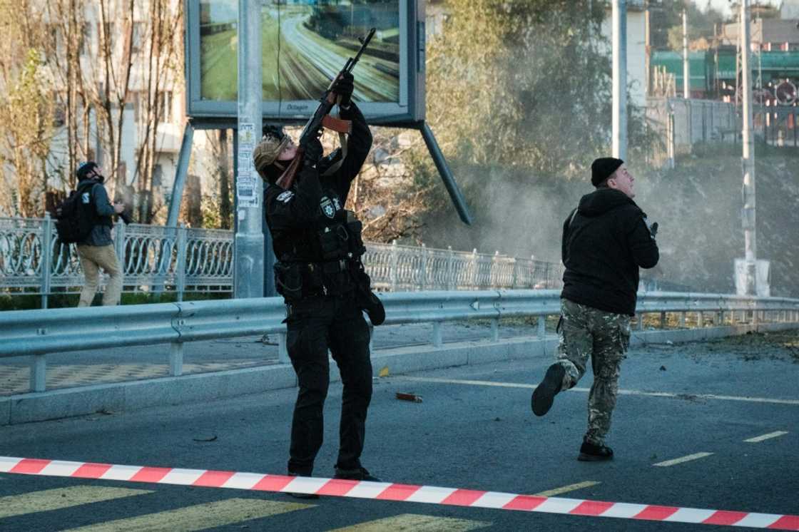 A police officer fires at a flying drone following attacks in Kyiv on October 17, 2022, amid the Russian invasion