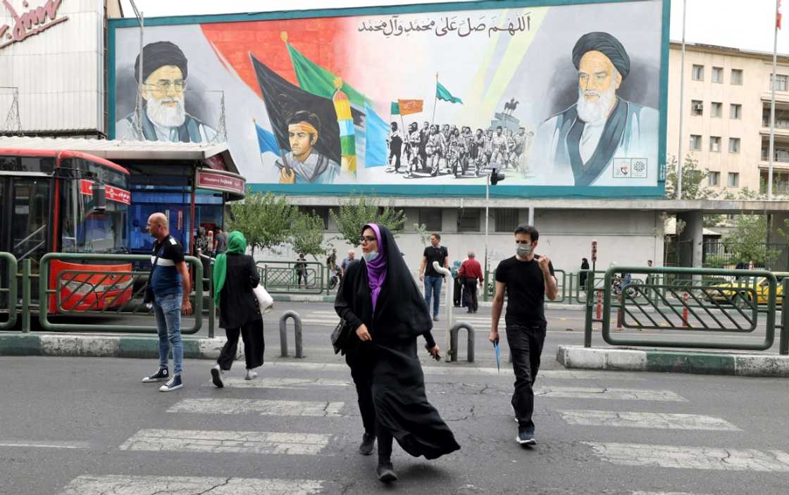 Iranians pass a billboard showing Iran's supreme leader Ayatollah Ali Khamenei and Ayatollah Ruhollah Khomeini (R) in Tehran, before the anti-regime protest movement began in September 2022 Iranians pass a billboard showing Iran's supreme leader Ayatollah Ali Khamenei and Ayatollah Ruhollah Khomeini (R) in Tehran, before the anti-regime protest movement began in September 2022