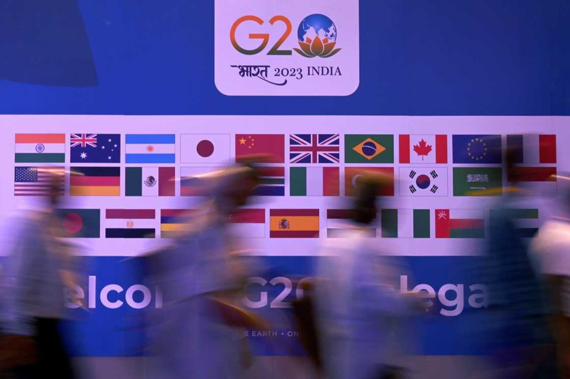 People walk past a banner with flags of countries participating in the G20 summit in New Delhi People walk past a banner with flags of countries participating in the G20 summit in New Delhi