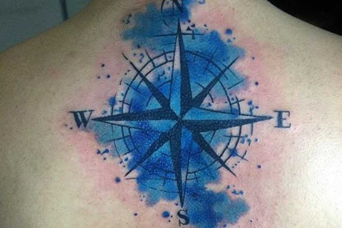 A man has a watercolour compass tattoo at the back A man has a watercolour compass tattoo at the back