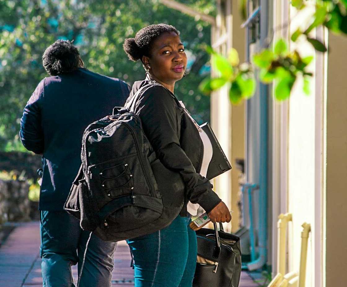 A woman walks away with a bag outdoors.