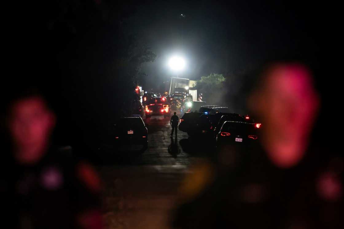 A first responder walks through the scene where a tractor-trailer was discovered with dozens of dead migrants  outside San Antonio, Texas; 50 deaths have been confirmed.