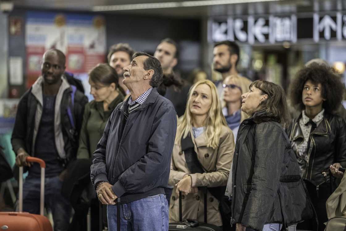 Travellers at an airport reacting to breaking-news alerts. Travellers at an airport reacting to breaking-news alerts.