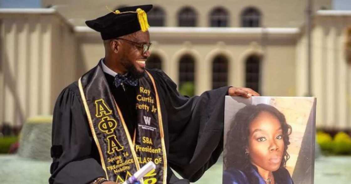 Black Man poses with a photo of a family member as he becomes a lawyer