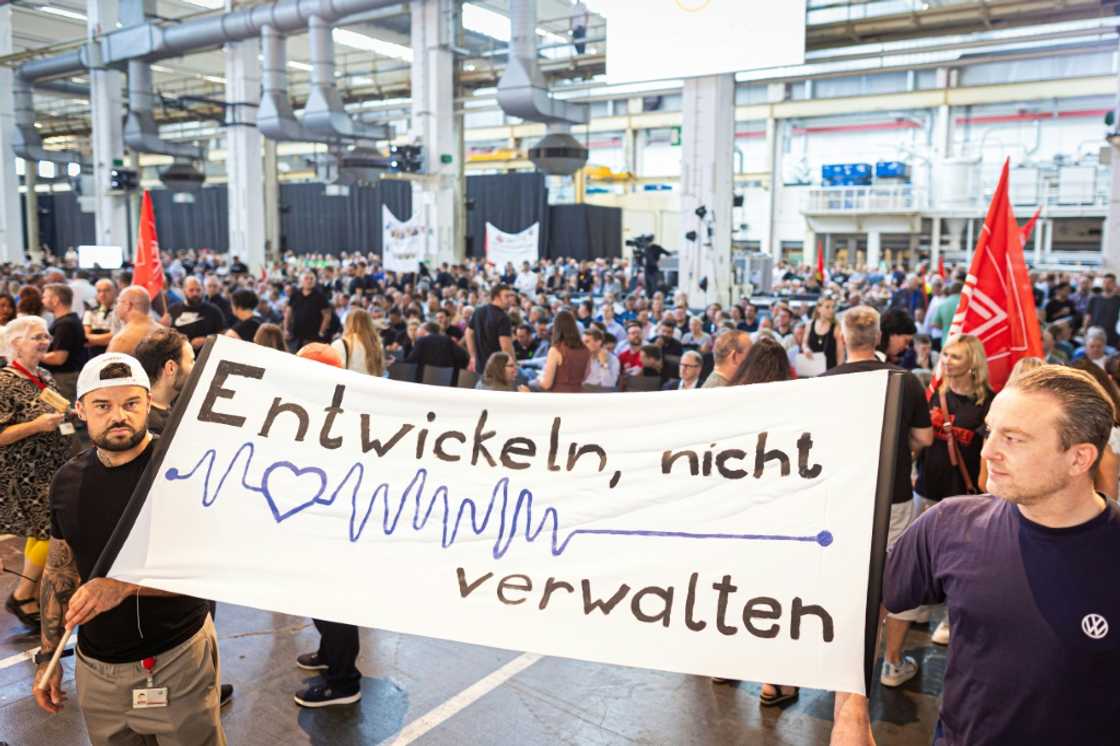 Employees of German automaker Volkswagen (VW) hold a banner that reads 'Grow, don't just manage'