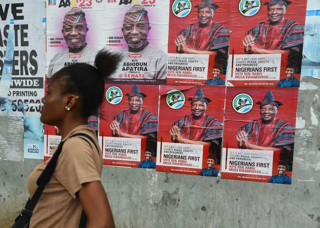 A woman walks past campaign posters of presidential aspirant of New Nigeria Peoples's Party (NNPP) Rabiu Kwankwaso.