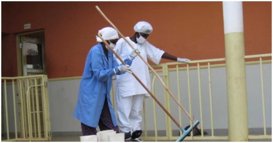 Mask-clad health workers do some cleaning, outside an emergency ward in a hospital Mask-clad health workers do some cleaning, outside an emergency ward in a hospital